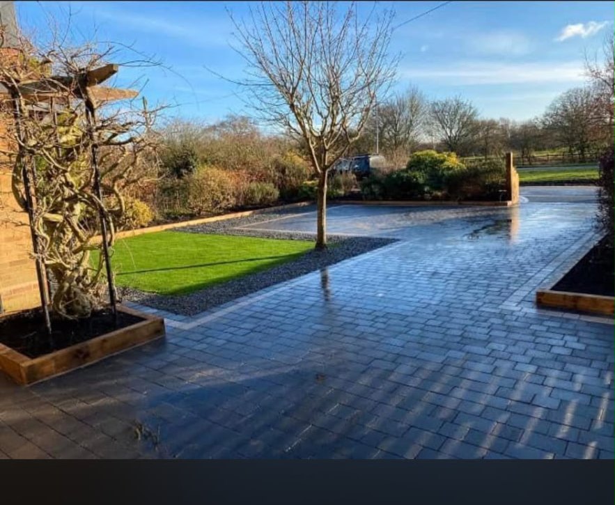 Large block paved driveway with lawn and planters