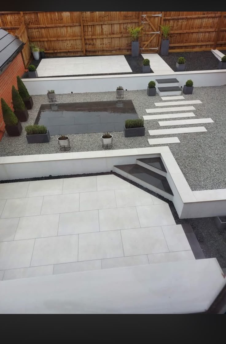 Modern split level porcelain patio with rendered walls and water feature